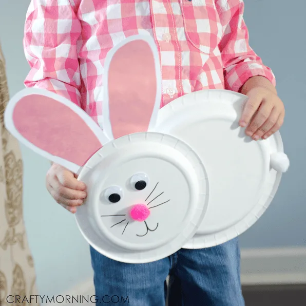 kid holding a pink and white paper plate bunny craft