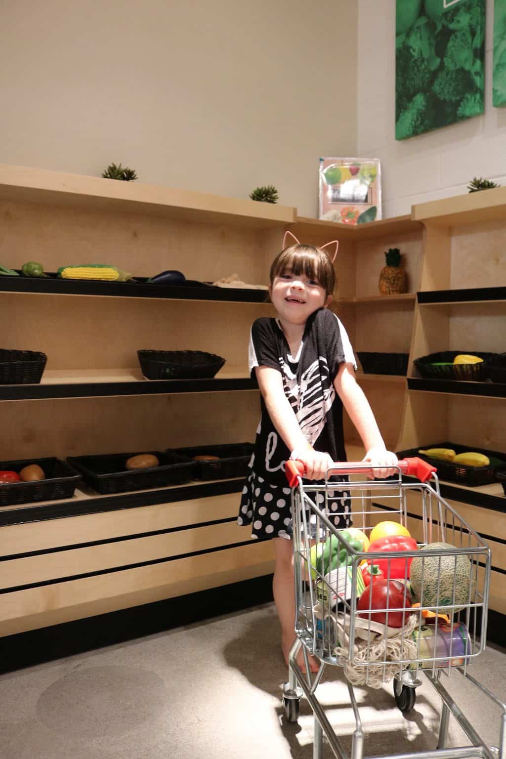 Little girl playing in the grocery store at Cayton Children's Museum in Santa Monica
