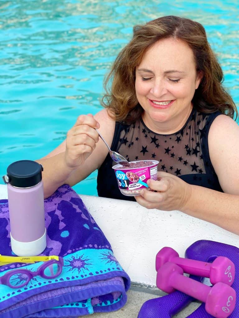 a woman eating joybol after working out in the pool