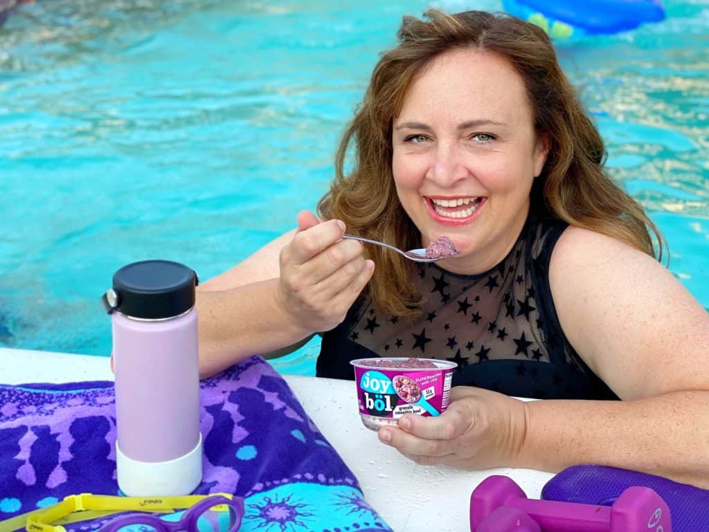 a woman eating joybol after working out in the pool